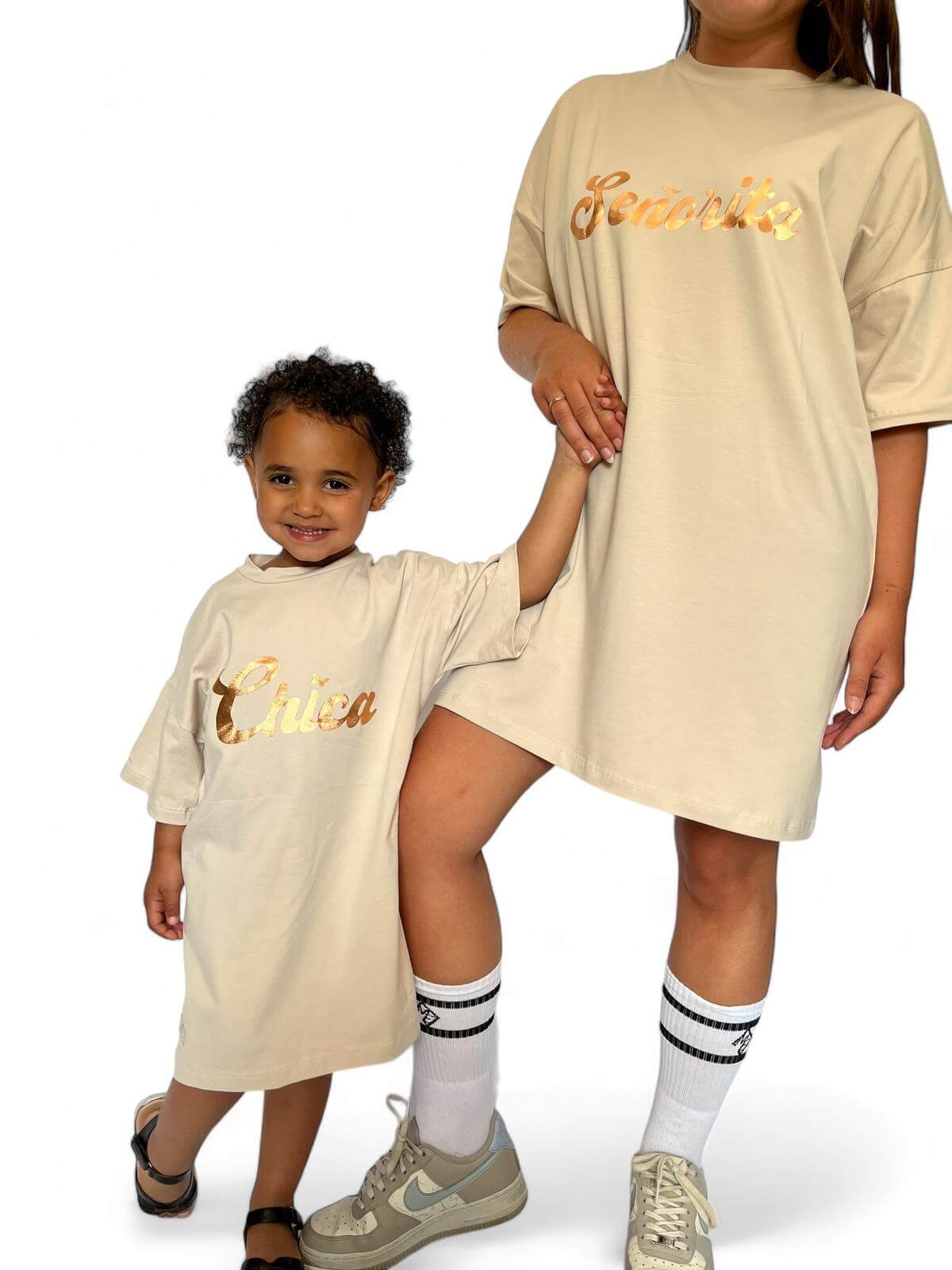 Vooraanzicht beige oversized T-shirt jurk met gouden opdruk 'Senorita' – vrouw hand in hand met klein meisje in dezelfde jurk