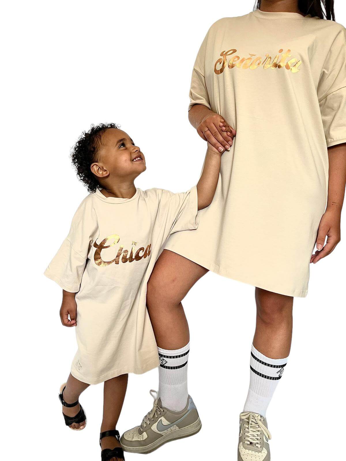 Voorkant oversized T-shirt jurk met gouden opdruk 'Senorita' – vrouw hand in hand met mini-me die naar moeder kijkt.